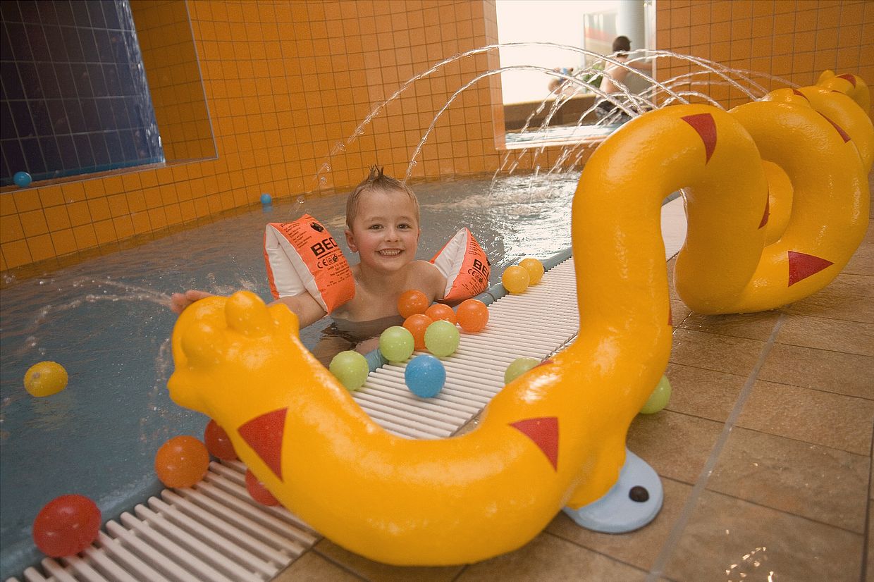 Ein Junge planscht glücklich im Kinderbereich