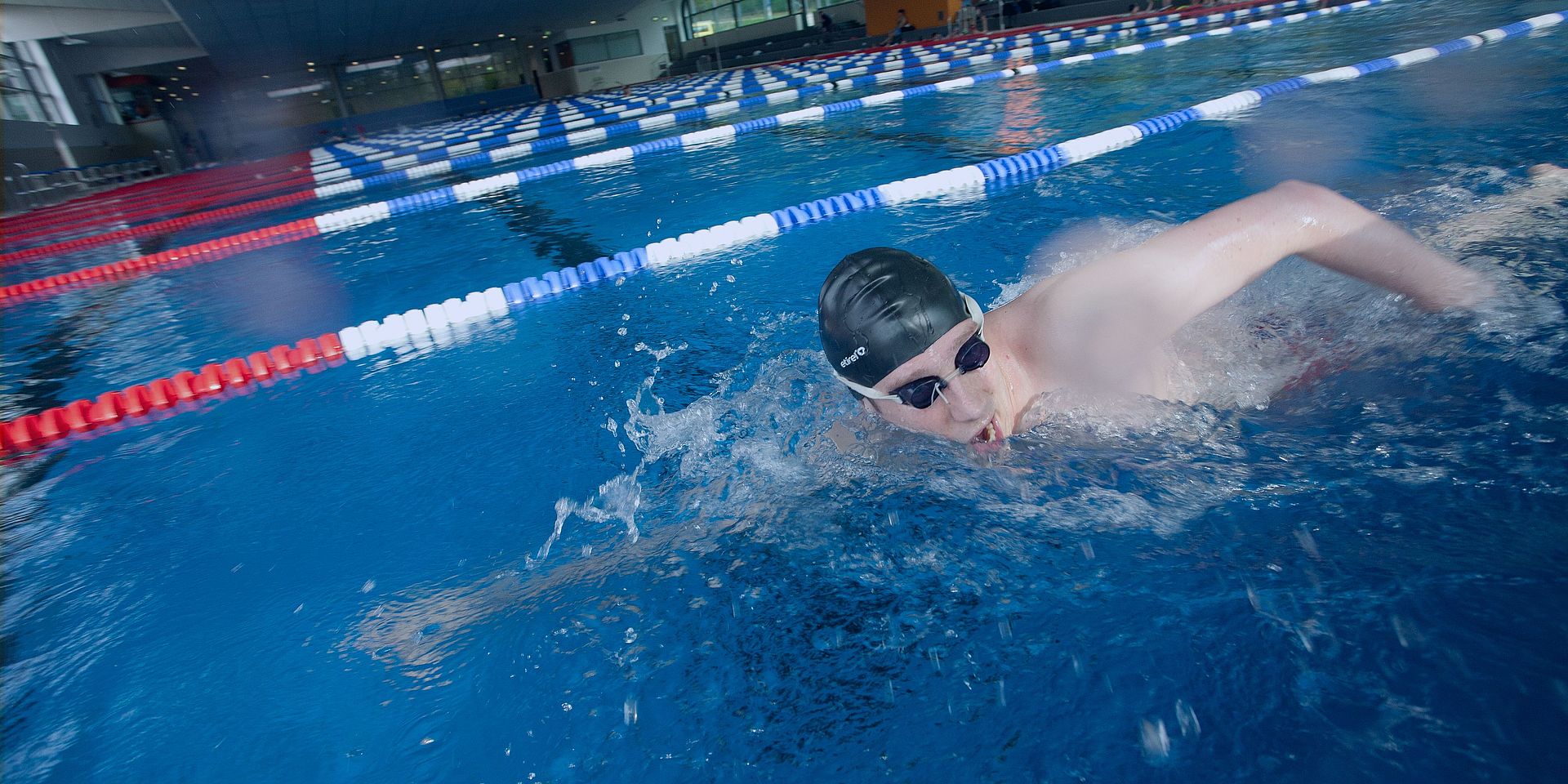 Ein Mann krault im Sportbecken