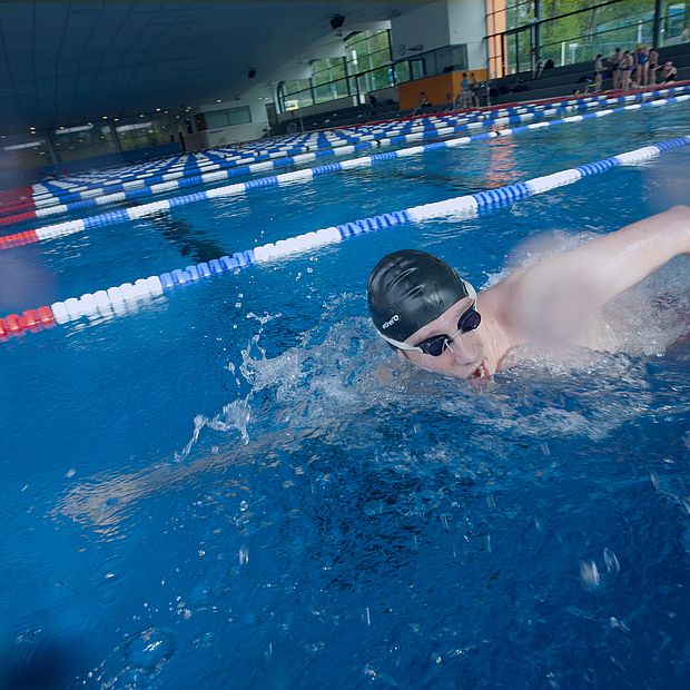 Ein Mann krault im Sportbecken