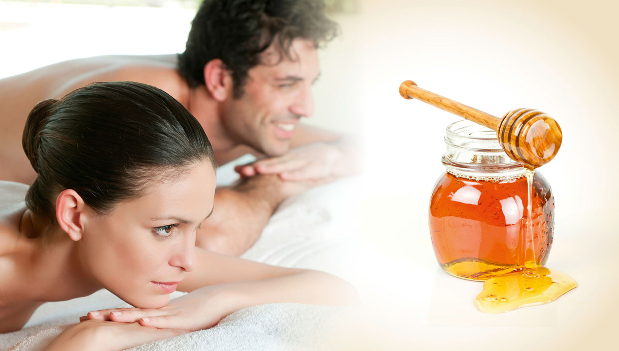 Pärchen liegen auf den Massageliegen und schauen auf das Honig-Öl