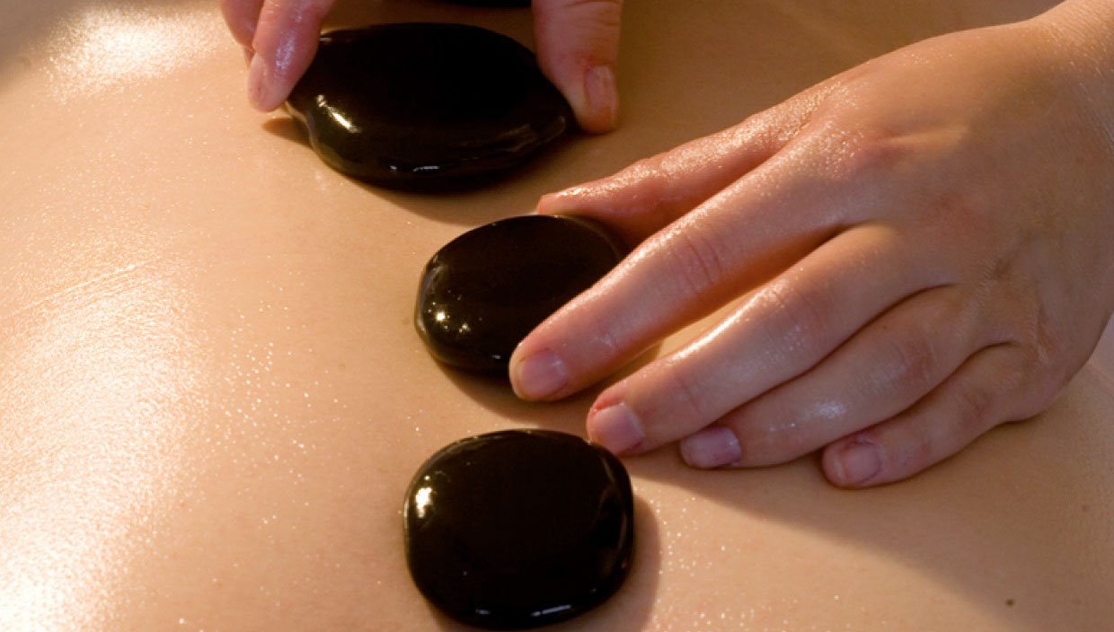 Die Steine für die Hot Stone Massage werden auf den Rücken des Kunden aufgelegt
